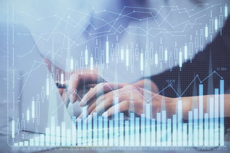 Multi exposure of woman hands typing on computer and financial graph hologram drawing. Stock market...