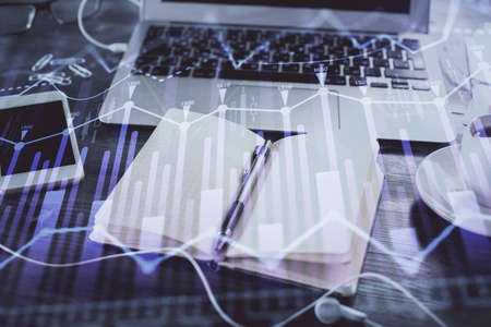 Multi exposure of financial graph drawings and desk with open notebook background. Concept of forex