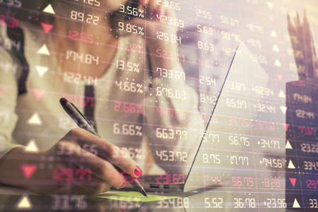 Double exposure of woman hands typing on computer and financial graph hologram drawing. Stock market...