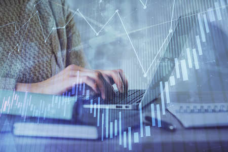 Double exposure of woman hands typing on computer and forex chart hologram drawing. Stock market...