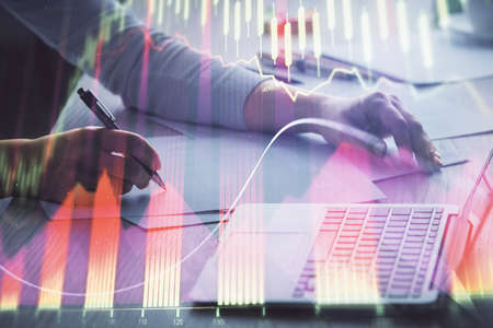 Double exposure of businesswoman hands typing on computer and forex chart hologram drawing....