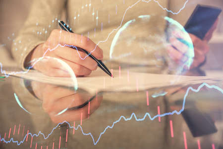 Double exposure of forex chart sketch hologram and woman holding and using a mobile device....