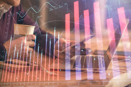 Double exposure of mans hands holding and using a phone and financial graph drawing. Analysis...