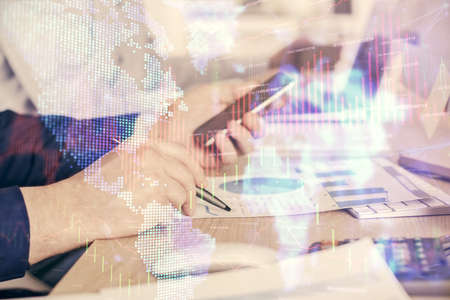 Double exposure of mans hands holding and using a digital device and forex graph drawing. Financial...