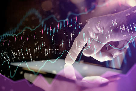 Double exposure of mans hands holding and using a digital device and forex graph drawing. Financial...
