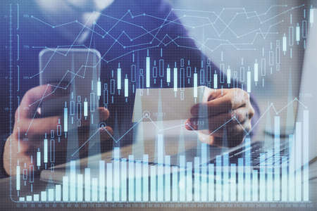 Double exposure of mans hands holding and using a phone and financial graph drawing. Analysis...