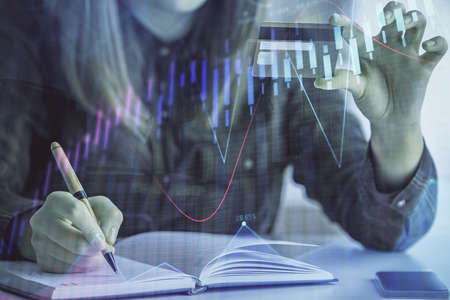 Double exposure of woman on-line shopping holding a credit card and financial graph drawing. Stock...