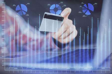 Double exposure of man hands holding a credit card and Forex graph drawing. Stock trading and...