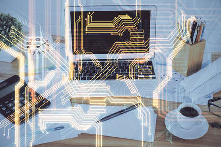 Computer on desktop in office with technology theme hologram. Double exposure. Tech concept.