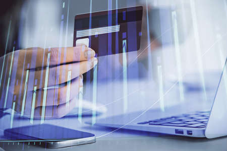 Multi exposure of woman on-line shopping holding a credit card and financial graph drawing. Stock...