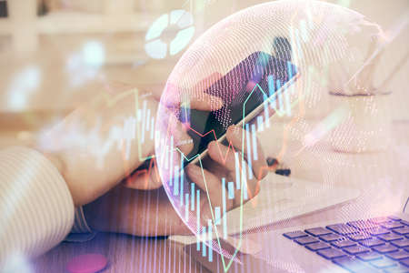 Double exposure of mans hands holding and using a digital device and forex graph drawing. Financial...