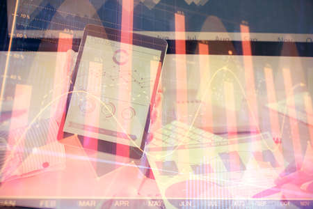 Double exposure of mans hands holding and using a digital device and forex graph drawing. Financial...