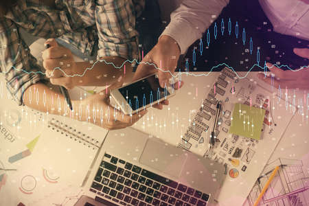 Double exposure of forex graph drawing and man and woman working together holding and using a mobile...