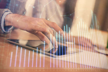 Double exposure of forex graph drawing and man and woman working together holding and using a mobile...