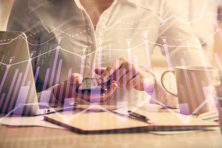 Double exposure of forex chart sketch hologram and woman holding and using a mobile device. Financial market concept.の写真素材