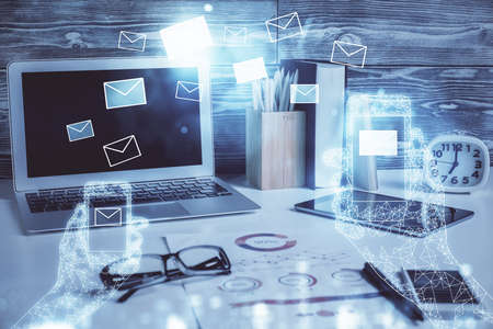 Desktop computer background in office and flying envelops hologram drawing. Double exposure. Electronic mail concept.の写真素材