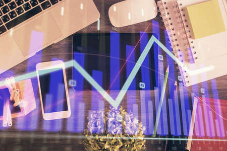 Double exposure of forex chart hologram over desktop with phone. Top view. Mobile trade platform...