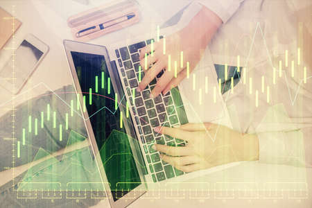 Double exposure of woman hands working on computer and forex graph hologram drawing. Top View....