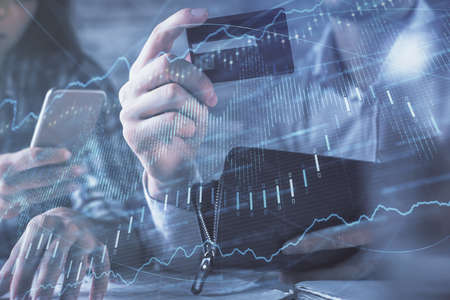 Double exposure of man and woman on-line shopping holding a credit card and forex graph hologram...