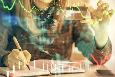 Multi exposure of woman on-line shopping holding a credit card and financial graph drawing. Stock...