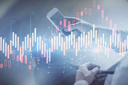 Double exposure of mans hands holding and using a digital device and forex graph drawing. Financial...