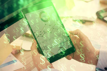 Double exposure of mans hands holding and using a phone and financial graph drawing. Analysis...