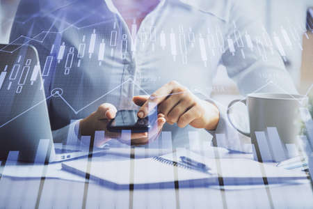 Double exposure of forex chart sketch hologram and woman holding and using a mobile device....