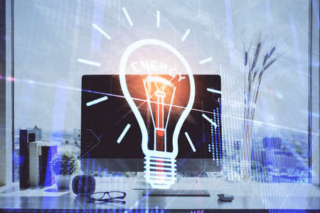 Computer on desktop in office with bulb icon hologram. Double exposure. Concept of idea.の写真素材