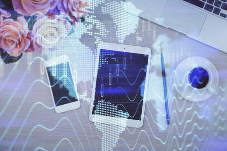 Double exposure of forex graph hologram over desktop with phone. Top view. Mobile trade platform...