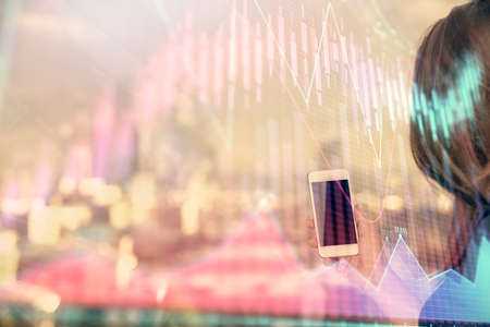Double exposure of forex chart sketch hologram and woman holding and using a mobile device. Stock market concept.の写真素材