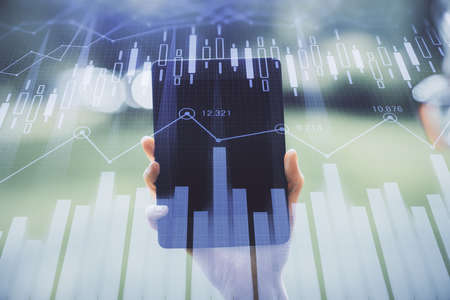 Double exposure of forex chart sketch hologram and woman holding and using a mobile device....