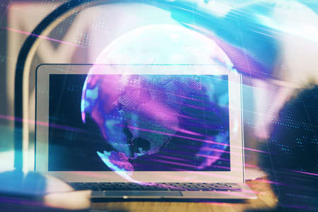 Computer on desktop in office with technology theme hologram. Double exposure. Tech concept.