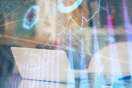 Stock market graph on background with desk and personal computer. Double exposure. Concept of financial analysis.の写真素材