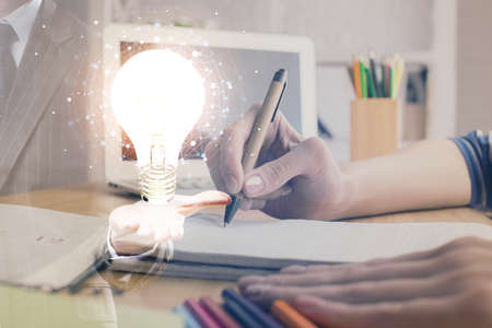 Drawing bulb over womans hands taking notes background. Concept of idea. Double exposure