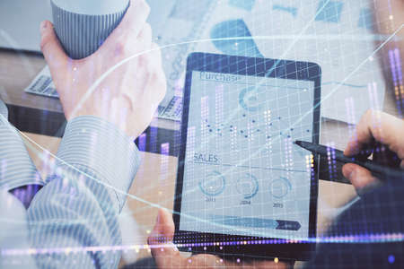 Double exposure of mans hands holding and using a phone and financial chart drawing. Market analysis...
