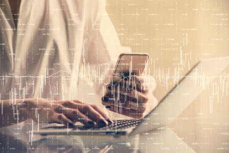 Double exposure of financial graph sketch hologram and woman holding and using a mobile device....