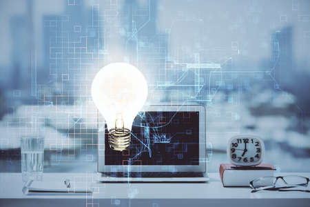 Computer on desktop in office with bulb icon hologram. Double exposure. Concept of idea.