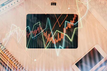 Double exposure of forex graph hologram over desktop with phone. Top view. Mobile trade platform...