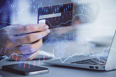 Multi exposure of woman on-line shopping holding a credit card and financial graph drawing. Stock...