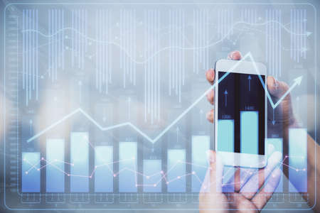 Double exposure of forex graph sketch hologram and woman holding and using a mobile device. Stock...