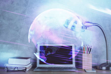 Computer on desktop in office with technology theme hologram. Double exposure. Tech concept.