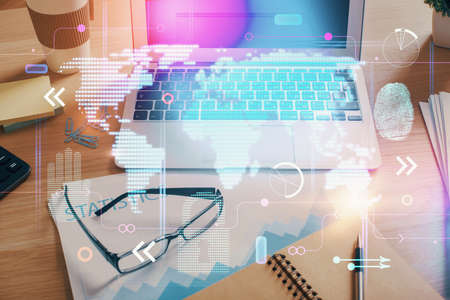 Double exposure of desktop with computer and world map hologram. International data network concept.