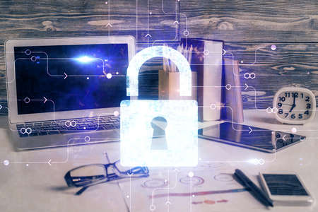 Double exposure of desktop with computer and lock icon hologram. Concept of data safety.
