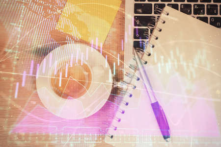 Double exposure of financial chart drawing over table background with computer. Concept of research and analysis. Top view.の写真素材