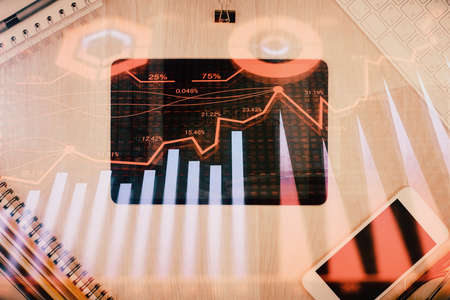 Double exposure of forex graph hologram over desktop with phone. Top view. Mobile trade platform concept.の写真素材
