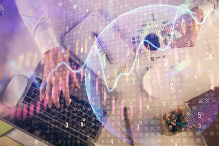 Multi exposure of mans hands typing over computer keyboard and forex graph hologram drawing. Top...