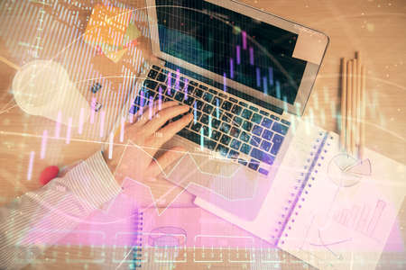 Double exposure of mans hands typing over computer keyboard and forex graph hologram drawing. Top...