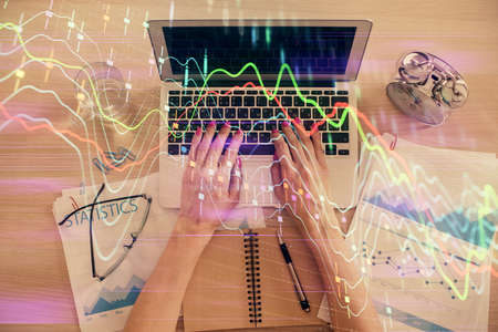 Double exposure of woman hands working on computer and forex graph hologram drawing. Top View....