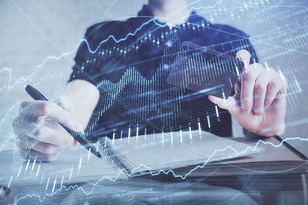 Double exposure of man hands holding a credit card and Forex graph drawing. Stock trading and...