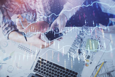 Double exposure of forex graph drawing and man and woman working together holding and using a mobile...